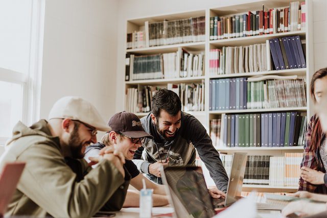 Hombres trabajando y sonriendo en una biblioteca