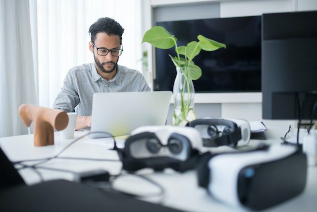 Hombre trabajando y lentes Oculus difuminados