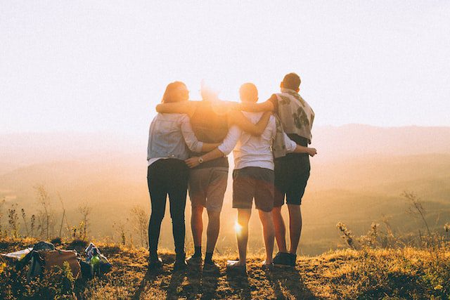 Amigos abrazados en una paisaje de montaña al atardecer